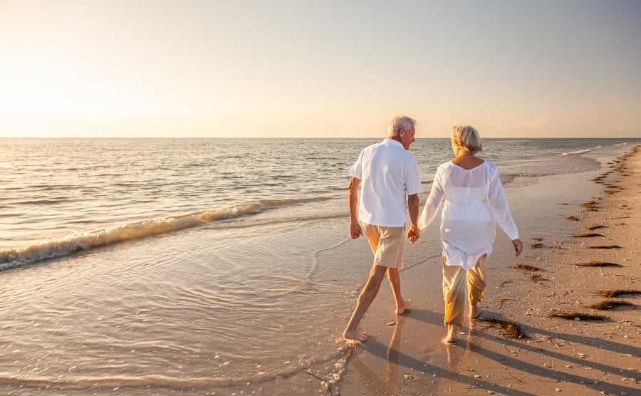 Mature couple holding hands while walking on a beach