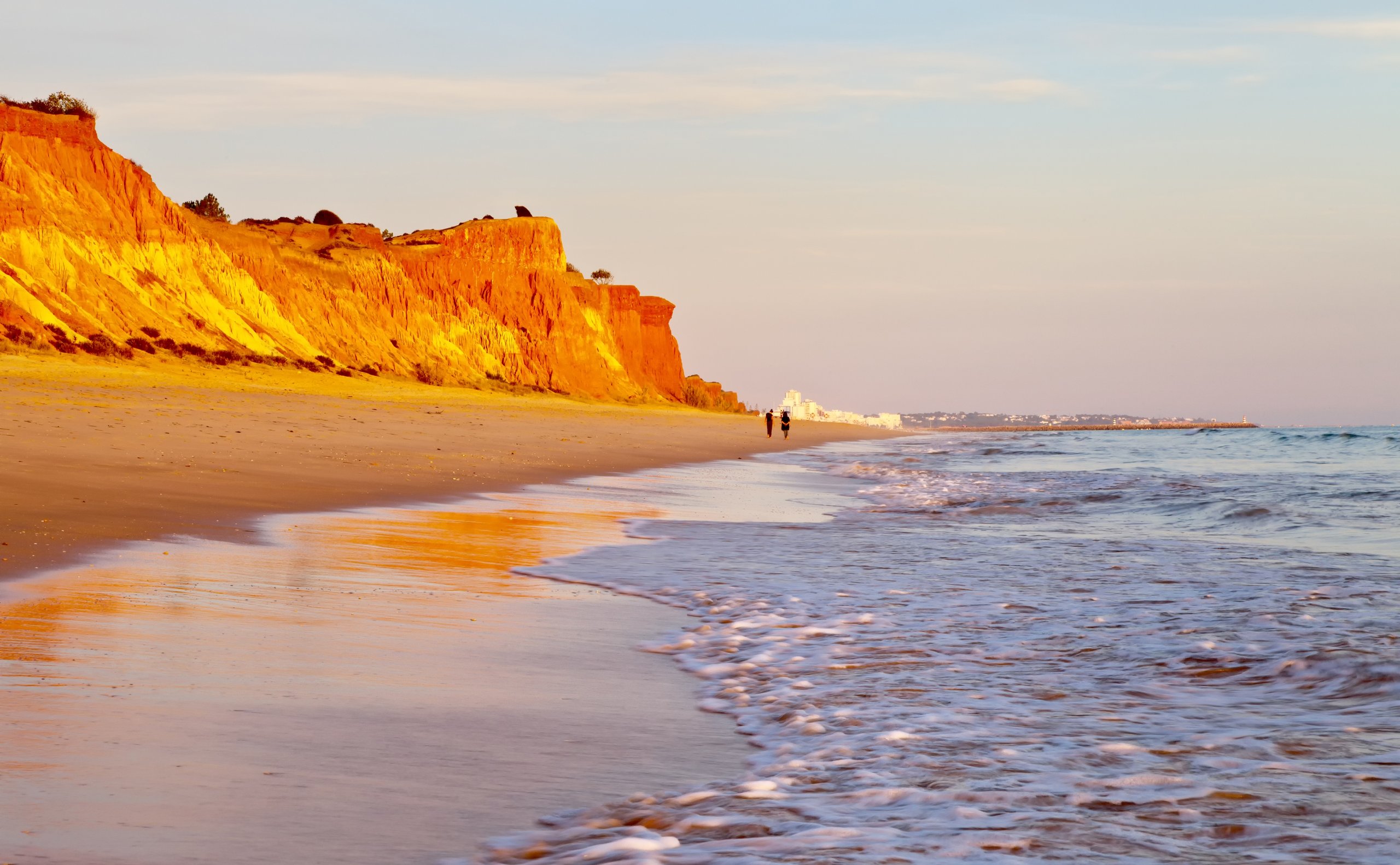 Beautiful Praia da Falesia near the city of Vilamoura with a shallow sandy beach fringed with unusual red rocks at sunset.