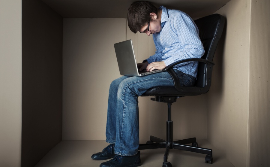 Man hunched over laptop in small room