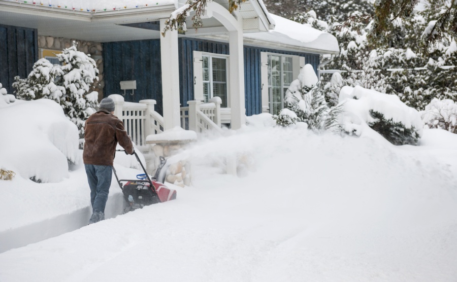 Man with snow blower cuts path to snow-covered Canada home