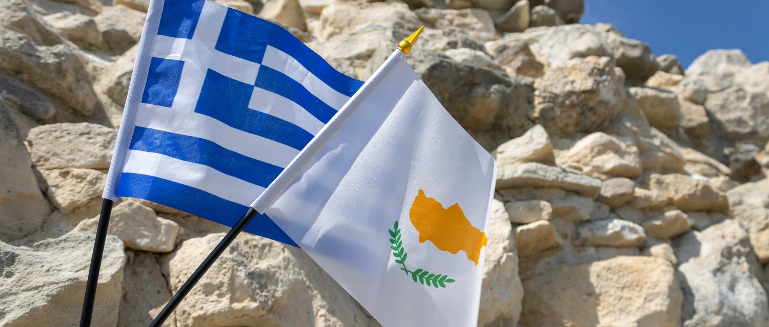 Greece and Cyprus flags in front of an old stone wall