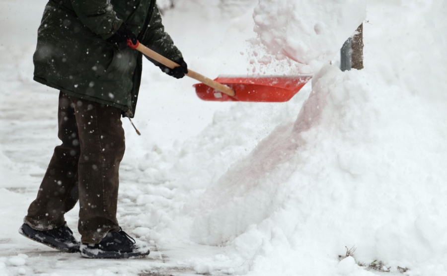 A person using a shovel to clear back snow banks