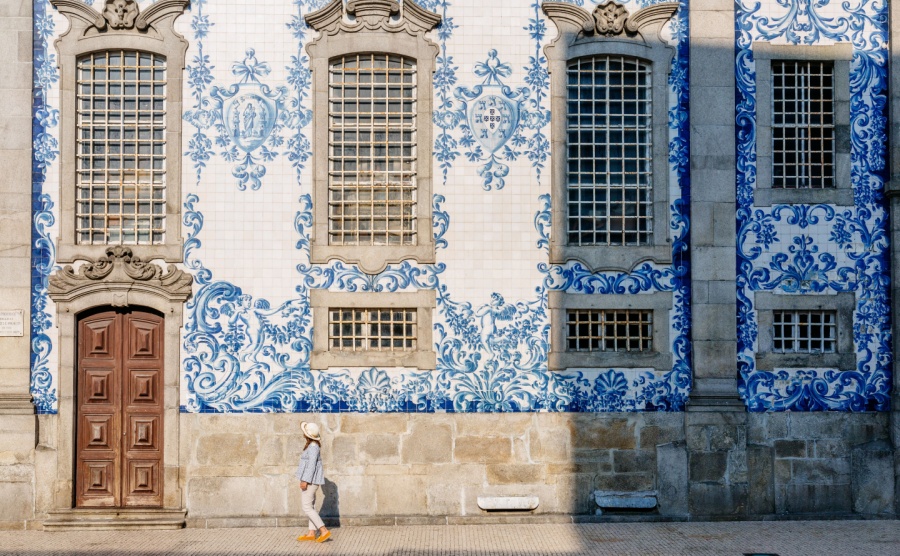 A tourist walks in front of a pretty building in Porto